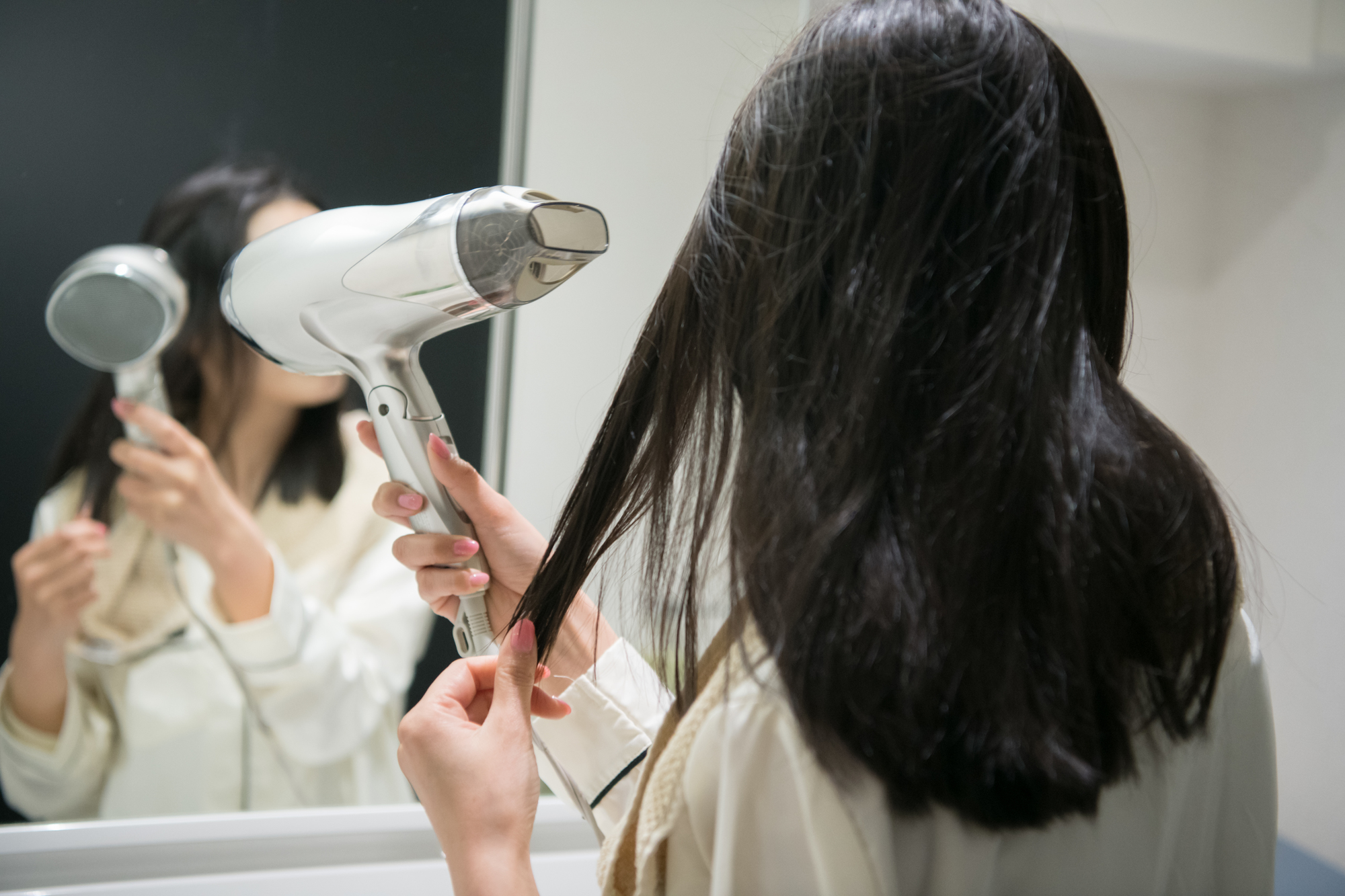 ドライヤーで髪を乾かす女性